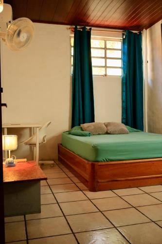 a bedroom with a bed with blue curtains and a window at Panama Beach Lodge in San Carlos