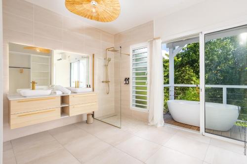 a bathroom with two sinks and a tub and a window at Villa Andrea in Case-Pilote