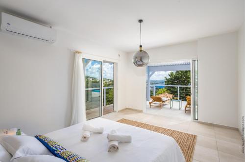 a white bedroom with a bed and a balcony at Villa Andrea in Case-Pilote