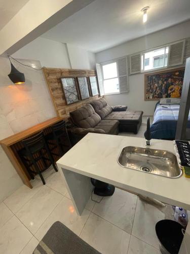 a kitchen and living room with a sink and a couch at Som do mar Kitinete in São Vicente