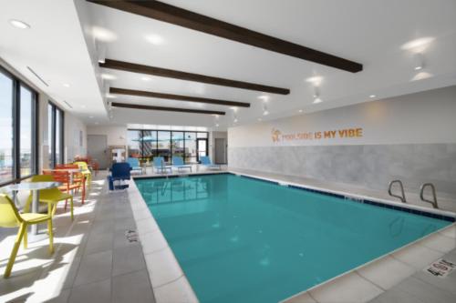 a pool in a hotel room with chairs and a table at Home2 Suites By Hilton Albuquerque Airport in Albuquerque