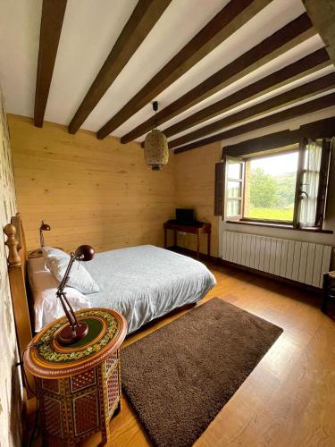a bedroom with a bed and a table with a lamp at Posada Rural Valoria in Valoria
