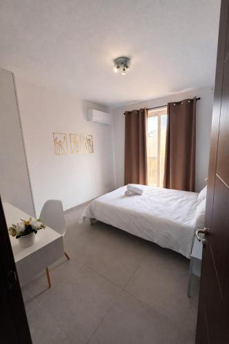 a bedroom with a bed and a table and a window at Msida Modern & Bright 2-Bedroom Apartment in Msida