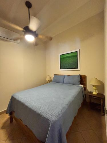 a bedroom with a blue bed and a ceiling fan at St. Francis Suite in San Juan del Sur