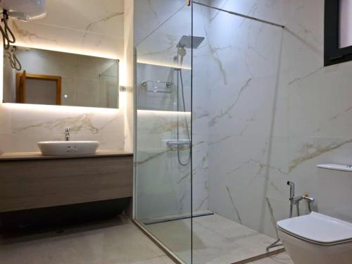 a bathroom with a glass shower and a sink at Elegant 3-room apartment in Dakar