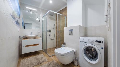 a bathroom with a washing machine and a sink at Dom Horizon Park 3A in Dziwnówek