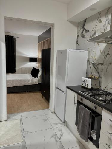 a kitchen with a white refrigerator and a bedroom at Luxury rooms in Ashton under Lyne