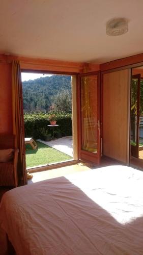 a bedroom with a bed and a large glass window at Maison du vieux chêne in Grimaud