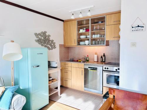 a kitchen with a blue refrigerator and wooden cabinets at Ferienwohnung Westerlicht - Apartment am Leuchtturm - De Torenhoeve in Nieuw-Haamstede