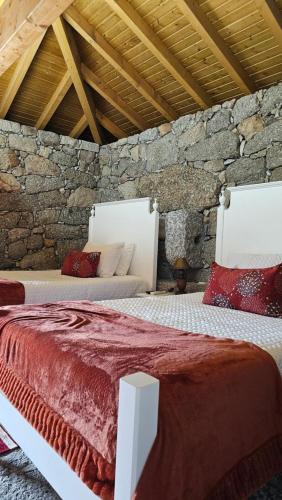 two beds in a room with a stone wall at Quinta Lama de Cima in Fafe