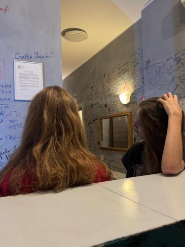 a woman sitting at a table getting her hair cut at Gloria Hostel Milano in Milan