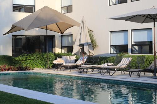 a pool with chairs and umbrellas next to a building at Casa Begonias Hotel mas Villas in Jiutepec