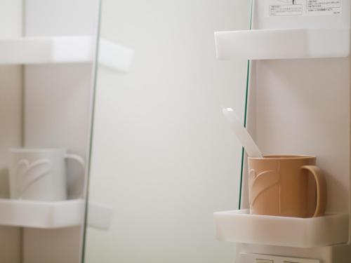 a cup sitting on a shelf next to a mirror at 貸別荘 ウサギの郷 in Fujikawaguchiko