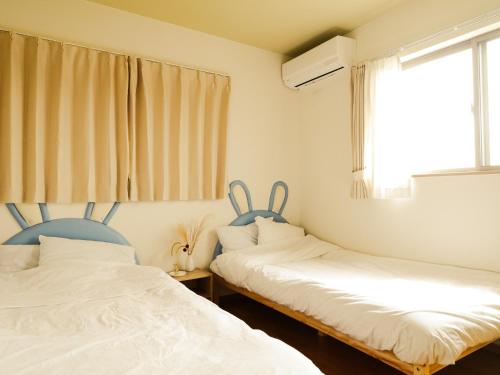 two beds in a room with a window at 貸別荘 ウサギの郷 in Fujikawaguchiko
