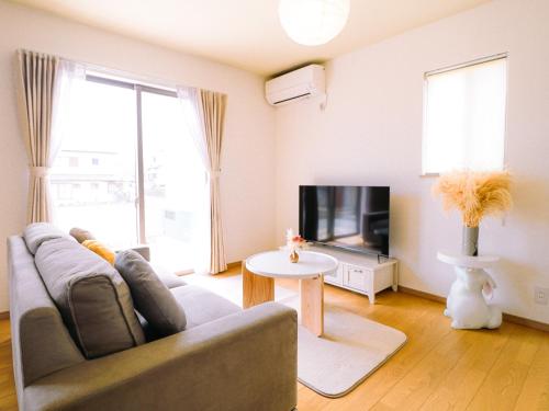 a living room with a couch and a tv at 貸別荘 ウサギの郷 in Fujikawaguchiko