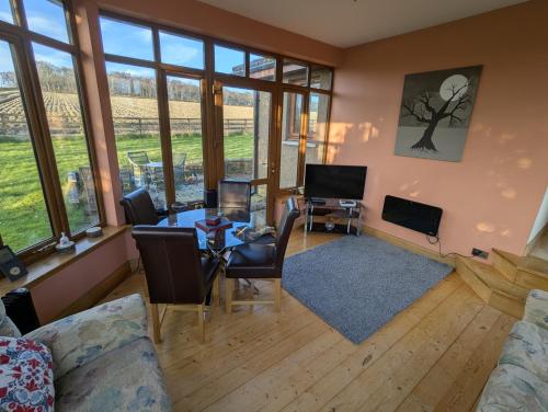 a living room with a table and chairs and windows at Wester Muirhouse in Linlithgow