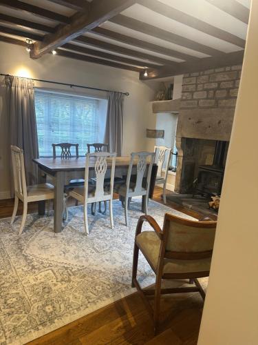 a dining room with a table and chairs and a fireplace at Thatch End Cottage in Baslow