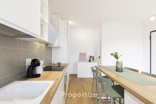 a kitchen with white cabinets and a counter with chairs at Verde Appartamento Moderno in Monserrato