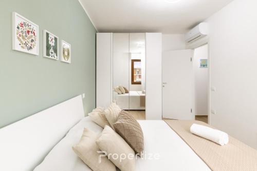 a white bedroom with a bed and a bathroom at Verde Appartamento Moderno in Monserrato