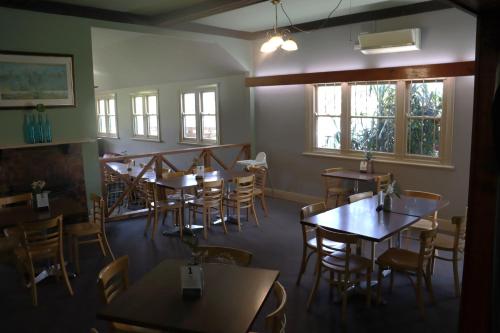 a dining room with tables and chairs and windows at Flowerdale Hotel in Flowerdale