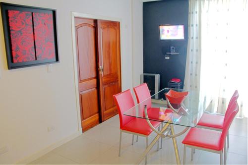a dining room with a glass table and red chairs at Dunas I, 3 in Pinamar