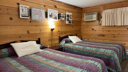 two beds in a room with wooden walls at Walla Walla Garden Motel in Walla Walla