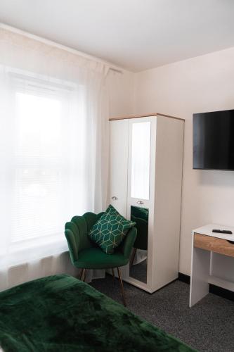 a bedroom with a green chair and a mirror at Bristol Boutique Stay in Bristol