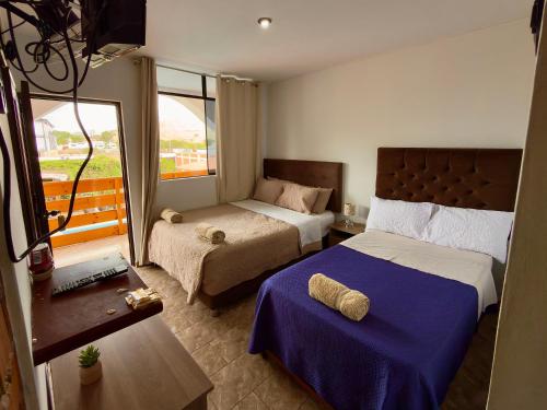 a hotel room with two beds and a window at Huacachina Desert House in Ica