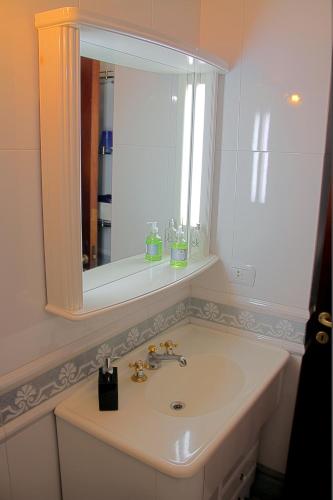 a white bathroom with a sink and a mirror at Dunas I, 3 in Pinamar