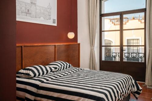a bedroom with a bed with a black and white striped blanket at Casa Serdán in Puebla