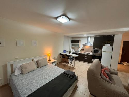 a bedroom with a bed and a couch and a kitchen at Alquilaencanarias El Palm Mar in Palm-Mar