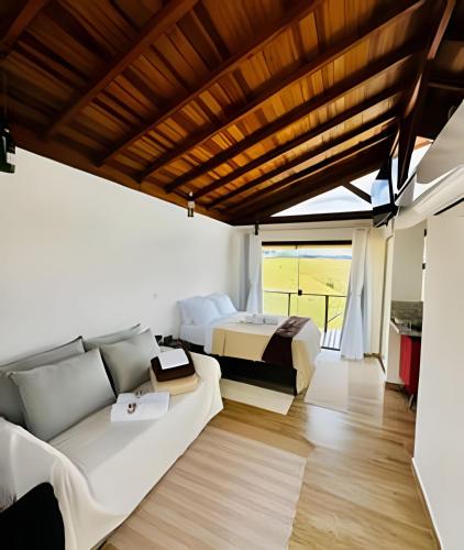 a living room with a couch and a bed at Vinhedo Villarejo - Chalés do Vinhedo in Paty do Alferes