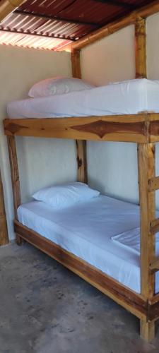 two bunk beds in a room with white sheets at Finca Hostal Eva Maria in Santa Marta