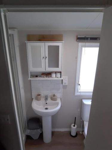 a white bathroom with a sink and a toilet at Joesphine Newquay Bay 37 in Newquay Bay Resort