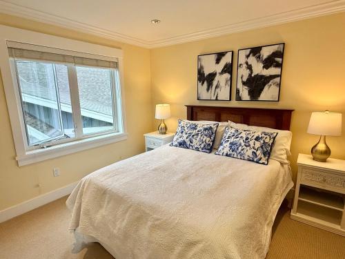 a bedroom with a bed with two lamps and a window at Qualicum Landing Beachside Home in Qualicum Beach