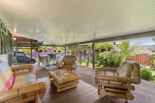 a covered porch with furniture and a table at Peaceful 2BR Garden Bungalow in Taravao