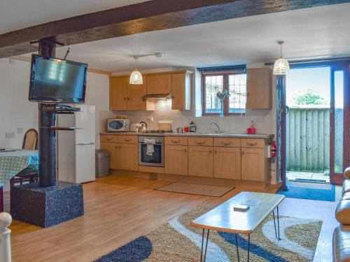 a kitchen with wooden cabinets and a tv in a room at Shire Cottage - Uk50029 in Liskeard