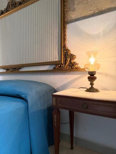 a lamp on a table next to a bed at Dimora 400 - nel cuore del Centro Storico di Lecce in Lecce