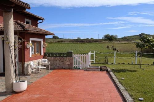 a house with a white fence and a field at Casa de campo La Casuca Del Monje, San Vicente de la Barquera in La Acebosa