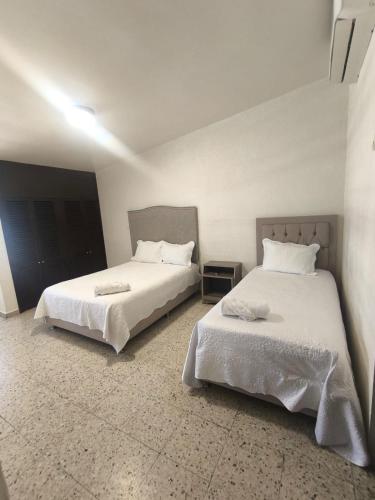 two beds in a hotel room with white sheets at Casa 25 Centrica con 3 recamaras in Hermosillo
