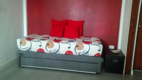 a bed with red pillows and a red wall at Dunas I, 3 in Pinamar