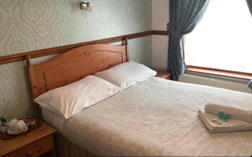 a bedroom with a bed with a wooden headboard and a window at Dover's Restover Bed & Breakfast in Dover