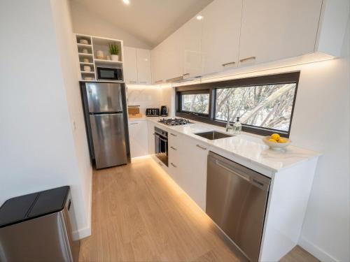 a kitchen with white cabinets and a sink and a window at Mount Buller Alpine Chalet Mountain Views Sleeps up to 12 in Mount Buller