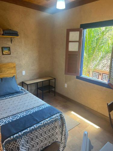 a bedroom with a bed and a large window at Pousada Condado Santa Maria in Baependi