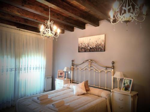 a bedroom with a bed and a chandelier at Del Abuelo Casa Rural in Prádena del Rincón