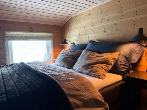 a bed in a room with a wooden wall at Panoramahytte in Norheimsund