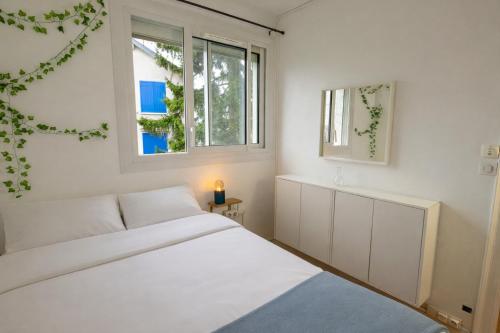a white bedroom with a bed and two windows at Une Maison en centre ville in Cholet