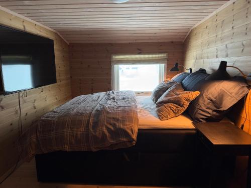 a bedroom with a bed with pillows and a television at Panoramahytte in Norheimsund