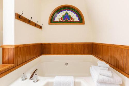 a bathroom with a bath tub with a stained glass window at Forest Home with Deck, EV Station, King Beds in Cambria