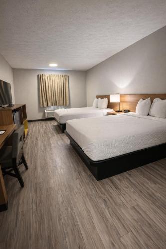 a hotel room with two beds and a desk at Days Inn by Wyndham Amherst OH - Near Cleveland Cedar Point & Lake Erie in Amherst